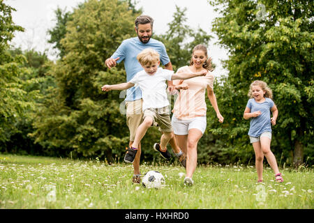 La famiglia che giocano a calcio nel parco e divertirsi Foto Stock