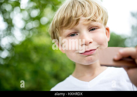 Bambino felice mangiando cioccolato cookie in estate presso il parco Foto Stock