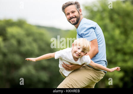 Padre gioca con il figlio e lo porta come un piano Foto Stock