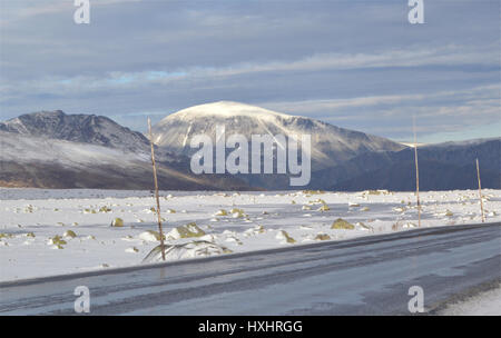 Paesaggio con la strada Bygdin in primo piano e cime innevate sullo sfondo. Da Jotunheimen, Norvegia. Foto Stock