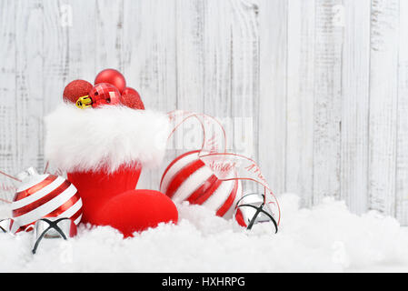 Red Santa's stivali con decorazioni di Natale in bianco sullo sfondo di legno Foto Stock