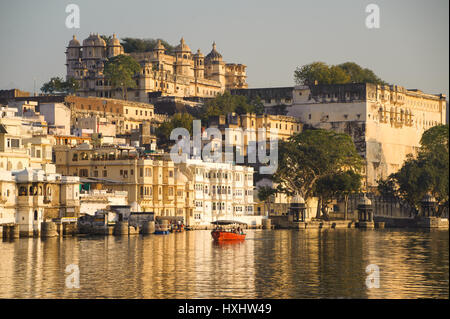 Una barca che porta i visitatori su Udaipur il Lago Pichola, vista palazzo di città come sfondo Foto Stock