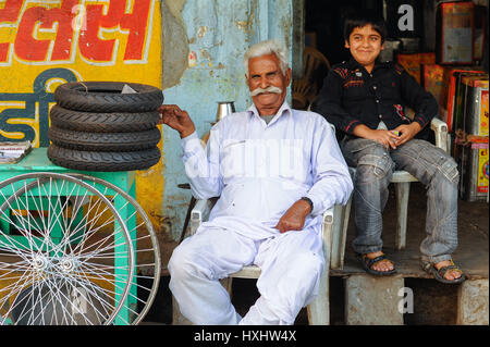 Un vecchio uomo e sua nipote sit orgogliosamente al di fuori delle loro parti di biciclette shop in Udaipur Foto Stock