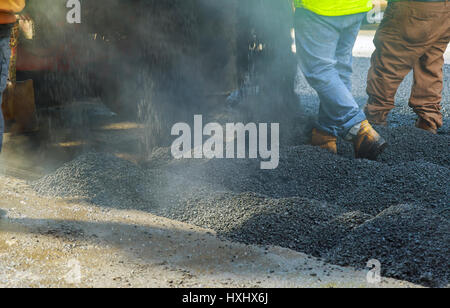 Gli uomini di lavoro duro sulla strada di asfaltatura con pale uomini strada è in costruzione Foto Stock