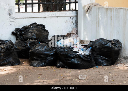 Nero sacchetti di rifiuti ammucchiati contro grungy parete urbano - Gibuti Africa orientale Foto Stock