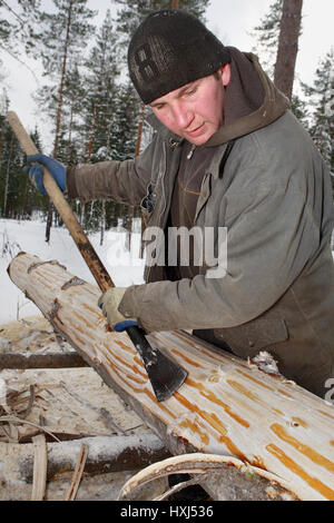 Regione di Leningrado, Russia - 2 Febbraio 2010: Il processo di distacco e di scortecciatura del legno, il peeling delle mani di rotoli con un drawknife. Foto Stock