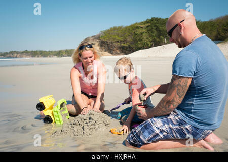 Famiglia di 3 giocando nella sabbia sulla spiaggia, padre, madre, figlio dei bimbi. Riviera Nayarit, Messico Foto Stock