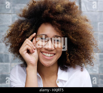 Ritratto di una donna sorridente con afro e bicchieri Foto Stock