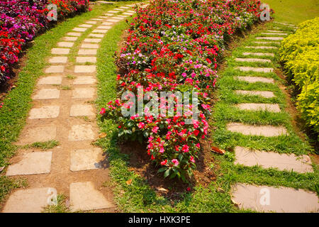 Luminoso giardino estivo piantato a fianco di piastrella di avvolgimento la passerella Foto Stock