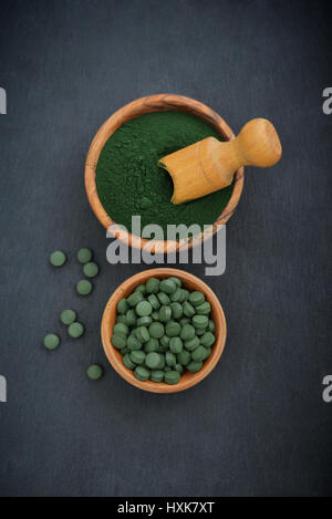 Massa spirulina e spirulina in pillole su nero ardesia sfondo Foto Stock