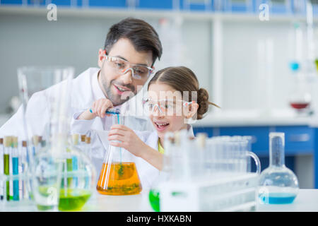 Uomo di insegnante e studente di ragazza di scienziati in occhiali di protezione rendendo esperimento in laboratorio Foto Stock
