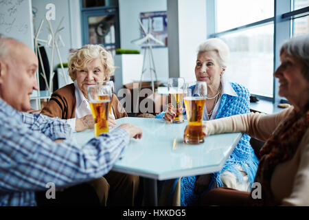 Senior amici riuniti in pub Foto Stock