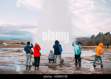 I turisti sono guardando l eruzione del Strokkur geyser in Islanda. Essa è parte del Haukadalur area geotermica e uno dei più famosi geyser Foto Stock