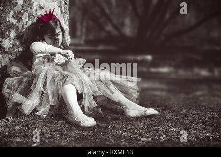 Annoiato princess; triste e solitaria bambina con corona rosa Foto Stock