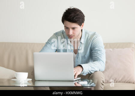 Giovane uomo che lavora a casa ufficio con computer laptop, freelan Foto Stock