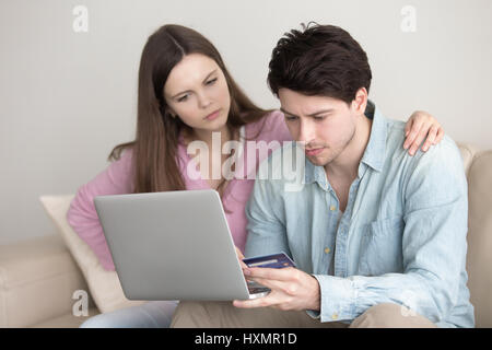 Coppia giovane acquisti, operazioni bancarie on line tramite laptop, carta di credito pr Foto Stock