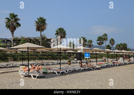 Kemer, Antalya, Turchia - Agosto 29, 2014: Villaggio Camuva, Mediterranea Resort turisti in vacanza si trovano in sedie a sdraio all'ombra di ombrelloni Foto Stock