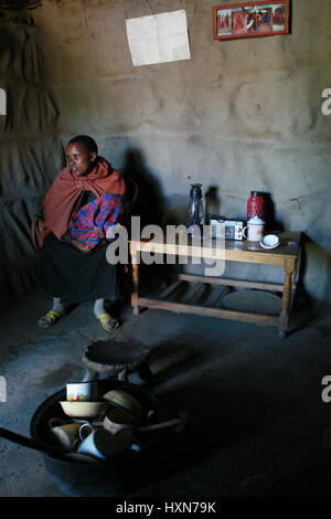 Meserani Snake Park, Arusha, Tanzania - Febbraio 14, 2008: vista interna della casa e semplice dei beni di persone africane tribù Masai, giovane donna sit Foto Stock