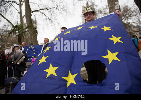 Il giorno che l'articolo 50 è stato invocato per avviare il processo di Brexit dall'Unione europea, i manifestanti si raccolgono in Westminster per mostrare il loro malcontento che la Gran Bretagna sarà a lasciare l'UE, il 29 marzo 2017 a Londra, Inghilterra, Regno Unito. Uno protester portando la bandiera dell'Europa con un foro nella bandiera vicino alla Casa del Parlamento. Foto Stock