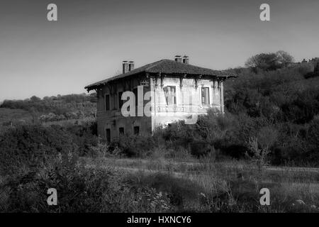 Vecchia stazione ferroviaria in disuso e fatiscenti, spicca tra la vegetazione circostante. Foto Stock