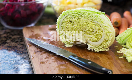 Cavolo verza con il coltello sul tagliere tagliate a metà Foto Stock
