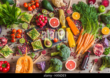 Sano cibo vegan. Panini e verdure fresche su sfondo di legno. Detox dieta. Colorati diversi succhi di frutta freschi. vista superiore Foto Stock