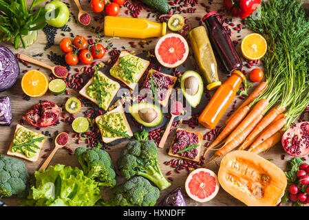 Sano cibo vegan. Panini e verdure fresche su sfondo di legno. Detox dieta. Colorati diversi succhi di frutta freschi. vista superiore Foto Stock