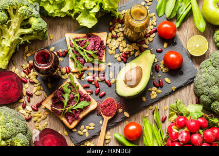 Sano cibo vegan. Panini e verdure fresche su sfondo di legno. Detox dieta. Colorati diversi succhi di frutta freschi Foto Stock