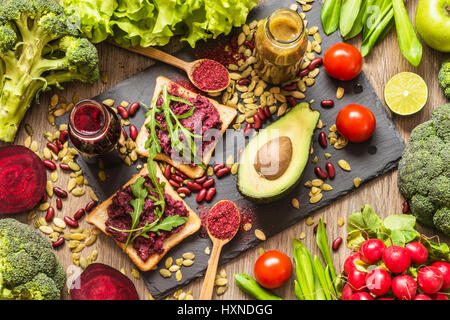 Sano cibo vegan. Panini e verdure fresche su sfondo di legno. Detox dieta. Colorati diversi succhi di frutta freschi Foto Stock