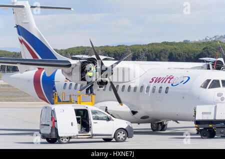 Mechanic sta facendo il servizio di manutenzione al piano ATR 42, della compagnia aerea Swiftair, parcheggiato al di fuori della pista, in Madrid - Barajas, Adolfo SUAREZ aeroporto. Foto Stock