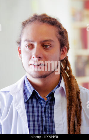 Giovane medico con lunghi dread si blocca in posa per la telecamera, clinica in background, concetto medico Foto Stock