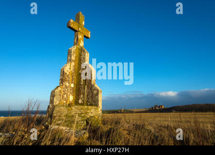 Croce di pietra sul tumulo di Mey, vicino al villaggio di Mey, Caithness in Scozia, Regno Unito. Castello di Mey nella distanza. Foto Stock