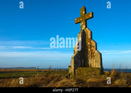 Croce di pietra sul tumulo di Mey, vicino al villaggio di Mey, Caithness in Scozia, Regno Unito. Dunnett in testa la distanza. Foto Stock