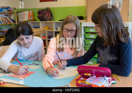 Tre ragazze che lavorano su una presentazione presso la scuola primaria Foto Stock