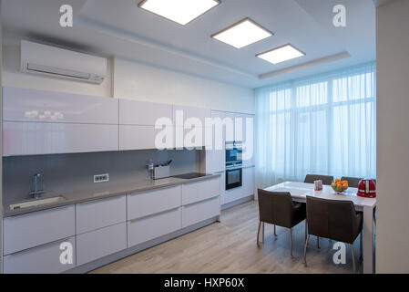 Cucina bianca con tavolo e grandi finestre Foto Stock