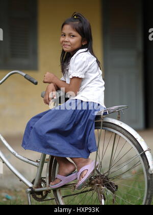 Il Khmer cambogiano ragazza scuola fuori scuola tradizionale nel sud della Cambogia sulla sua moto. I bambini in Cambogia tradizionale di usura uniformi scolastiche. Foto Stock