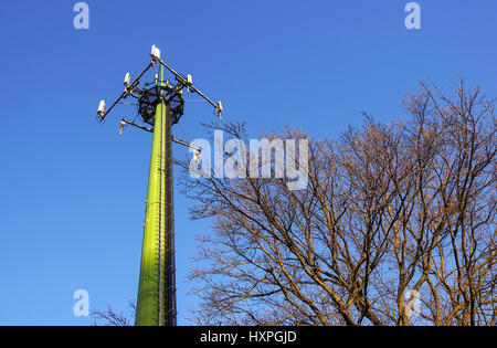 Acciaio torre di telecomunicazione con le antenne sul cielo blu e alberi Foto Stock