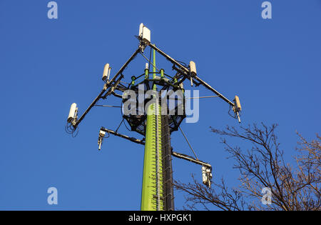Acciaio torre di telecomunicazione con le antenne sul cielo blu e alberi Foto Stock