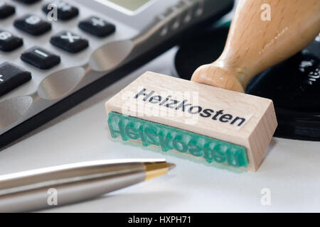 Timbro con etichetta i costi di riscaldamento si trova tra penna biro e calcolatrice tascabile, Stempel mit Aufschrift Heizkosten liegt zwischen Kugelschreiber und T Foto Stock