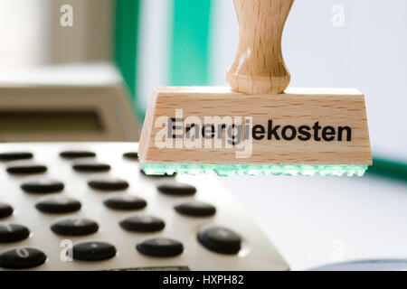 Timbro di stampa con i costi energetici si blocca sul timbro fiore circolare letto oltre calcolatrice tascabile e prima di file, Stempel mit Aufdruck Energiekosten hängt un S Foto Stock