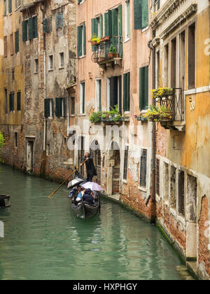 Gondola sul Canal Venezia sotto la pioggia con ombrelloni Foto Stock