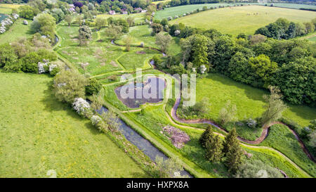 Vista aerea della campagna verde con campi, fattorie, prati, piccolo lago, fiume su un bordo del bosco, su una soleggiata giornata estiva . Foto Stock