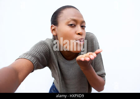 Selfie Ritratto di giovane donna africana soffia un bacio contro uno sfondo bianco Foto Stock