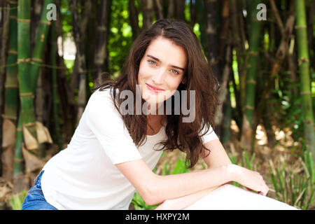 Ritratto di sorridente giovane donna di fronte alberi di bambù Foto Stock