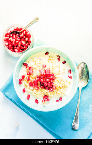 Porridge fatti in casa con i semi di melograno, overhead sul tavolo con spazio per la ricetta o testo. Di luminosi colori pastello.Estate il deposito, il concetto di benessere. Foto Stock