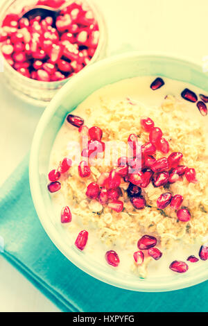 Porridge fatti in casa con i semi di melograno, overhead sul tavolo con spazio per la ricetta o testo. Di luminosi colori pastello.Estate il deposito, il concetto di benessere. Foto Stock