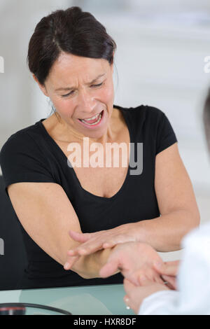 Donna che piange mentre medico ausculting suo Foto Stock