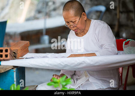 Donna monaco Fare cucito in Wat Phnom Sampeau tempio vicino Battambang, Cambogia, in Asia. Foto Stock