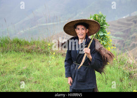 Yao Villaggio Dazhai, Longsheng, provincia di Guangxi, Cina - 3 Aprile 2010: sconosciuto contadino asiatici in cinese tradizionale hat, tra le terrazze di riso. Uno Foto Stock