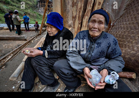 Villaggio Langde, Guizhou, Cina - 16 Aprile 2010: due anziani donna cinese contadino, le donne rurali, seduti vicino agriturismo nuove costruzioni rustiche celeb Foto Stock